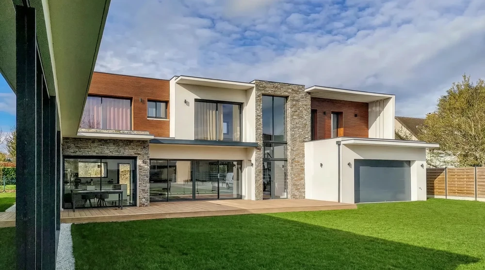 Maison contemporaine à deux niveaux, façade mixte : enduit blanc, bardage bois composite, parement pierre naturelle