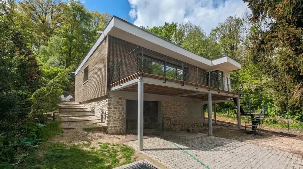 Maison contemporaine à ossature bois en cours de construction, implantée en forêt