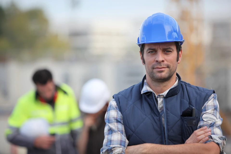 Chantier de construction avec deux professionnels en équipements de sécurité analysant des plans