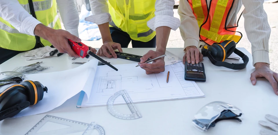 Équipe d'ingénieurs et d'architectes civils professionnels tenant un document de plan de projet, supervisant et contrôlant les travaux de construction sur le chantier de construction